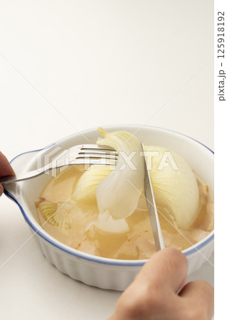 新玉ねぎの丸ごと煮込みスープの玉ねぎをフォークで持ち上げる 125918192