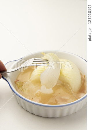 新玉ねぎの丸ごと煮込みスープの玉ねぎをフォークで持ち上げる 新玉ねぎの丸ごと煮込みスープの玉ねぎをフォークで持ち上げる 125918193