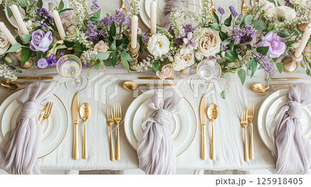 Elegant wedding table with floral centerpiece, gold accents and purple lavender details 125918405