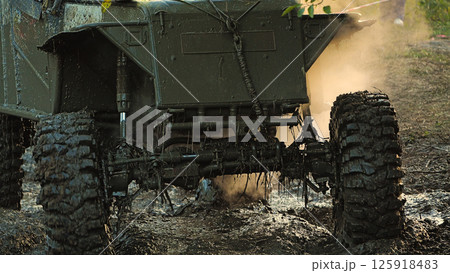 Close-up of muddy front end of a prepared off-road vehicle for heavy off-roading. A vehicle making its way through an obstacle course. The SUV has big wheels with wicked tread 125918483
