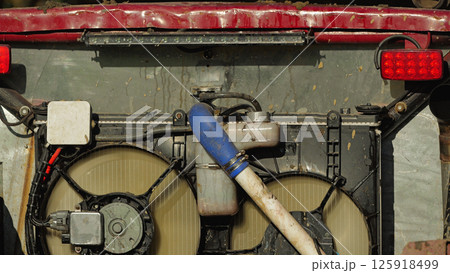 Close-up of the cooling system of a car. Radiator with pipes, fan and electronic components. Mounted on the rear of the SUV. Use in rough terrain Close-up of the cooling system of a car. Radiator with pipes, fan and electronic components. Mounted on the rear of the SUV. Use in rough terrain 125918499