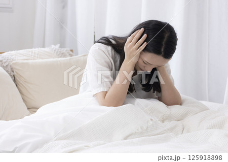 ベッドで頭を抱える女性 125918898