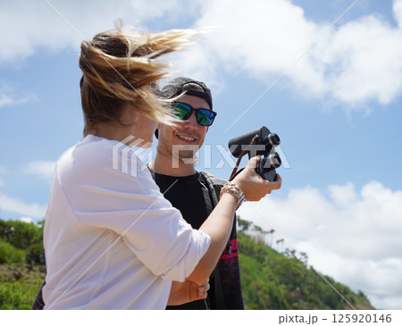 A man and a woman are intently looking through binoculars at something interesting in the distance 125920146
