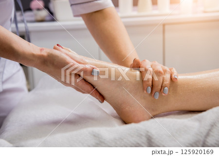 Beautiful young woman enjoying foot massage in spa salon. Cosmetology Beautiful young woman enjoying foot massage in spa salon. Cosmetology 125920169