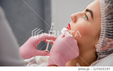 The doctor cosmetologist makes the facial injections procedure.  125920197