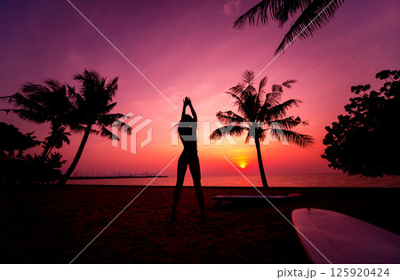 Silhouette of surfer girl with long surf board at sunset on tropical beach Silhouette of surfer girl with long surf board at sunset on tropical beach 125920424