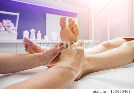 Beautiful young woman enjoying foot massage in spa salon. Cosmetology 125920461