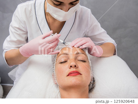The doctor cosmetologist makes the facial injections procedure. The doctor cosmetologist makes the facial injections procedure. 125920648