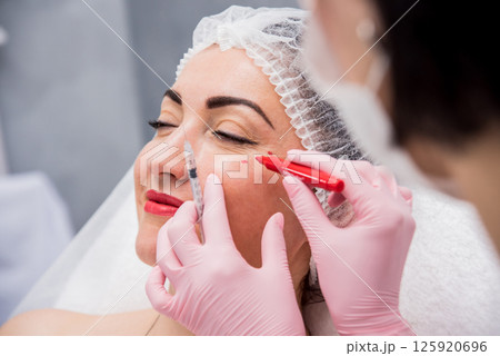 The doctor cosmetologist makes the facial injections procedure. The doctor cosmetologist makes the facial injections procedure. 125920696
