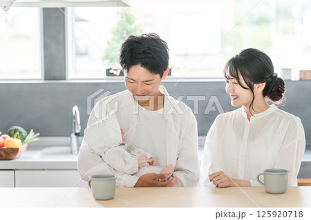 リビング・ダイニングで赤ん坊・赤ちゃんをあやす若い夫婦 リビング・ダイニングで赤ん坊・赤ちゃんをあやす若い夫婦 125920718