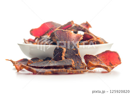 Beef jerky. Dried spiced meat isolated on white background. Beef jerky. Dried spiced meat isolated on white background. 125920820