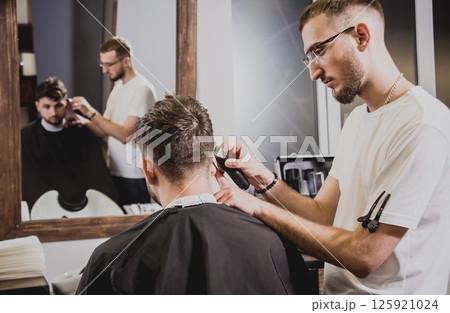 Young man with trendy haircut at barber shop.  125921024
