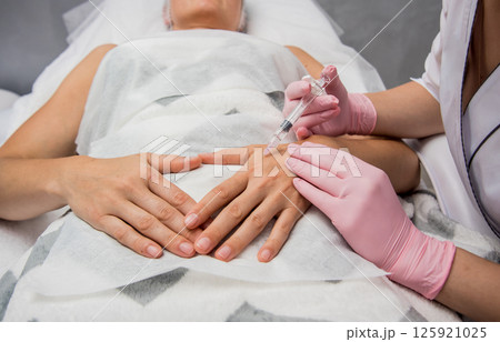 The doctor cosmetologist makes the arms injections procedure. The doctor cosmetologist makes the arms injections procedure. 125921025