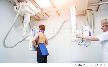 Radiologist and patient in a x-ray room. Classic ceiling-mounted x-ray system. Radiologist and patient in a x-ray room. Classic ceiling-mounted x-ray system. 125921034
