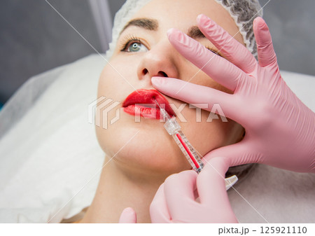 The doctor cosmetologist makes the facial injections procedure.  125921110