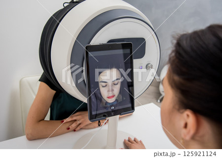 Face skin analyze system. Cosmetologist analyzing woman face.  125921124