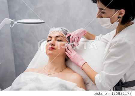 The doctor cosmetologist makes the facial injections procedure. The doctor cosmetologist makes the facial injections procedure. 125921177
