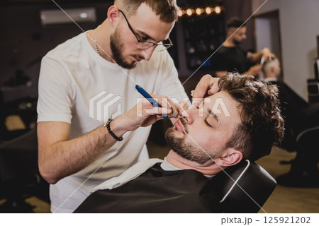 Young man with trendy haircut at barber shop. Young man with trendy haircut at barber shop. 125921202