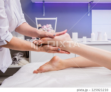 Beautiful young woman enjoying foot massage in spa salon. Cosmetology 125921210