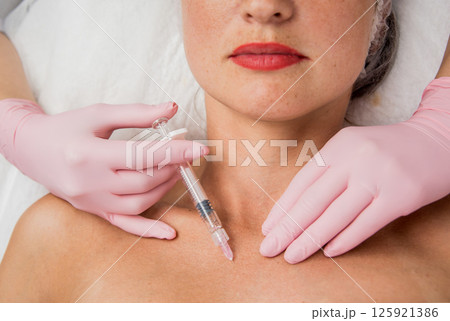 The doctor cosmetologist makes the neckline injections procedure. The doctor cosmetologist makes the neckline injections procedure. 125921386