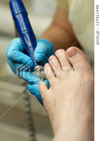Gloved technician performs dry pedicure with precision on toenails. Gloved technician performs dry pedicure with precision on toenails. 125921446