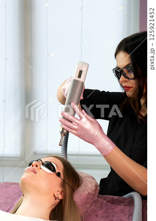 Esthetician adjusts laser device before eyebrow tattoo removal session 125921452