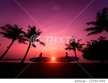 Silhouette of surfers couple holding long surf boards at sunset 125921493