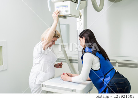 Radiologist and patient in a x-ray room. X-ray of human hand. Radiologist and patient in a x-ray room. X-ray of human hand. 125921505