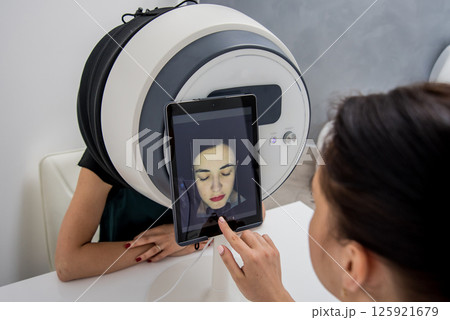 Face skin analyze system. Cosmetologist analyzing woman face.  125921679