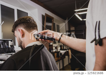 Young man with trendy haircut at barber shop.  125921686