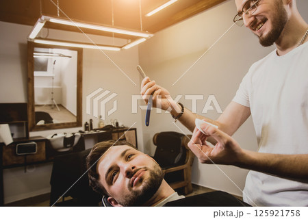 Young man with trendy haircut at barber shop. Young man with trendy haircut at barber shop. 125921758