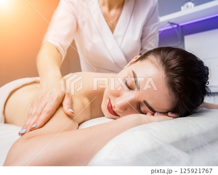Beautiful young woman enjoying massage in spa salon. Cosmetology Beautiful young woman enjoying massage in spa salon. Cosmetology 125921767