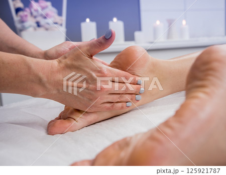 Beautiful young woman enjoying foot massage in spa salon. Cosmetology Beautiful young woman enjoying foot massage in spa salon. Cosmetology 125921787