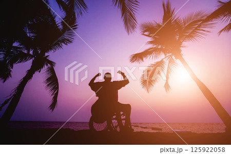 Disabled man in a wheelchair on the beach. Silhouette at sunset. 125922058