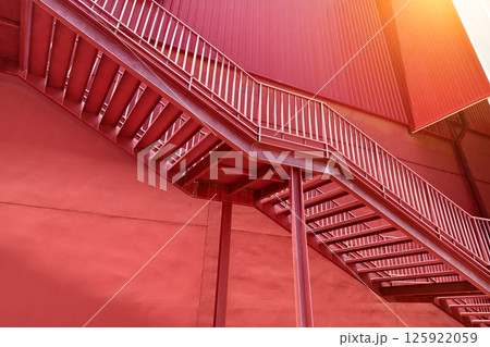 A set of stairs ascending a large red wall 125922059