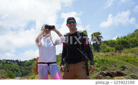 A man and a woman are intently looking through binoculars at something interesting in the distance A man and a woman are intently looking through binoculars at something interesting in the distance 125922100