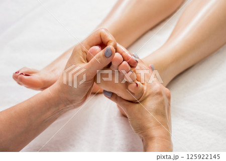 Beautiful young woman enjoying foot massage in spa salon. Cosmetology Beautiful young woman enjoying foot massage in spa salon. Cosmetology 125922145