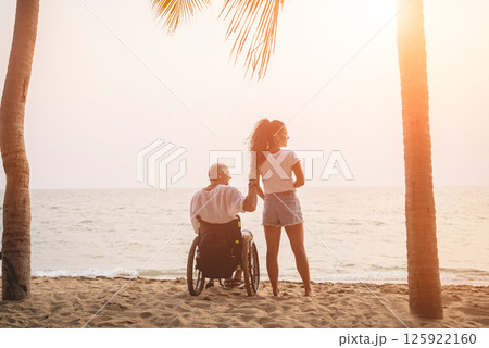 Disabled man in a wheelchair with his wife on the beach. 125922160