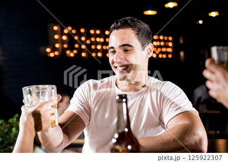 Cheerful friends in the pub. Drinking beer, talking, having fun. 125922307