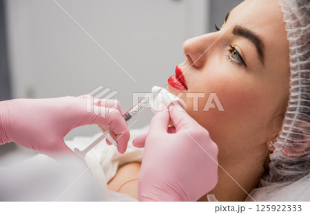 The doctor cosmetologist makes the facial injections procedure.  125922333