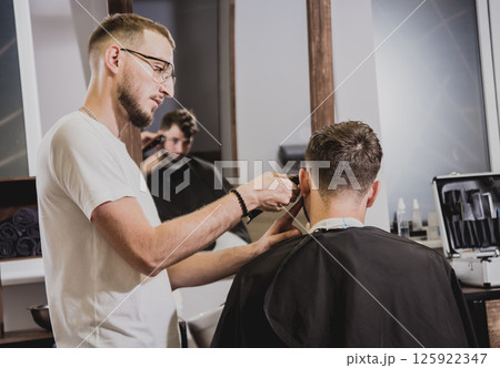 Young man with trendy haircut at barber shop.  125922347