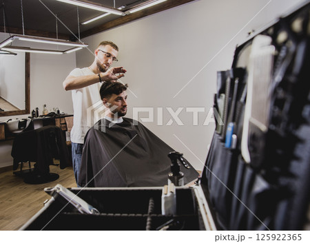 Young man with trendy haircut at barber shop.  125922365