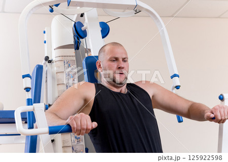 Disabled man doing strength exercises separate from the wheelchair. 125922598