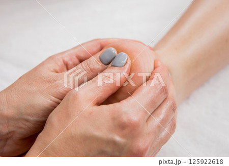 Beautiful young woman enjoying foot massage in spa salon. Cosmetology 125922618