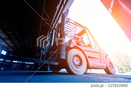 The big industrial forklift drives into the warehouse. The big industrial forklift drives into the warehouse. 125922666