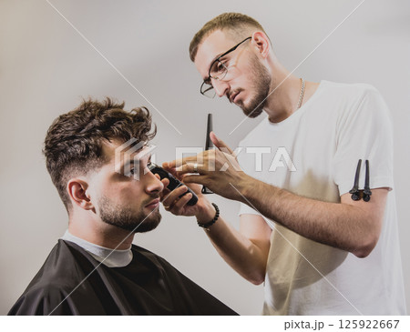 Young man with trendy haircut at barber shop.  125922667