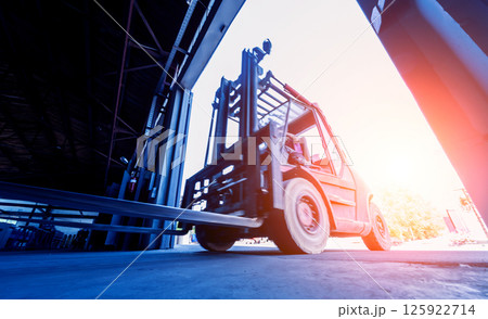 The big industrial forklift drives into the warehouse. 125922714
