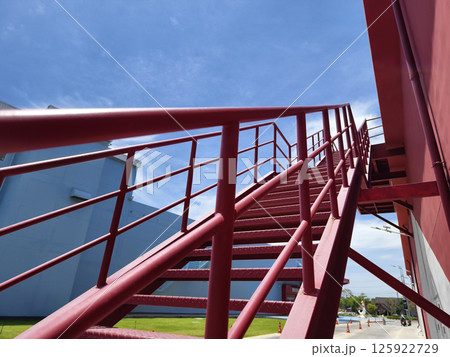 A set of stairs ascending a large red wall 125922729