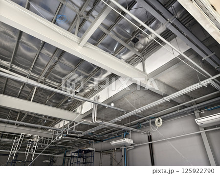 The ceiling of a large building under construction an extensive network of pipes The ceiling of a large building under construction an extensive network of pipes 125922790