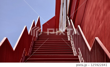 A set of stairs ascending a large red wall A set of stairs ascending a large red wall 125922841
